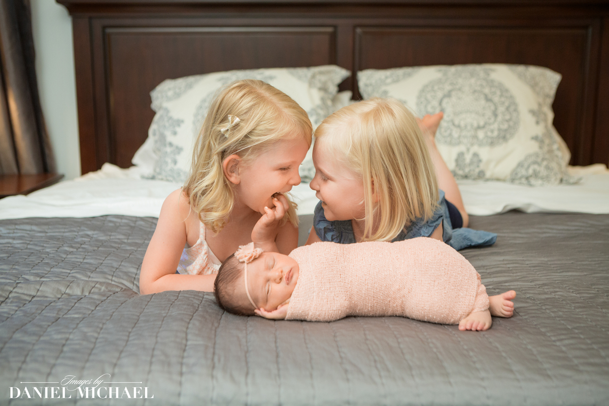 Two girls smiling at each other with baby sleeping in front